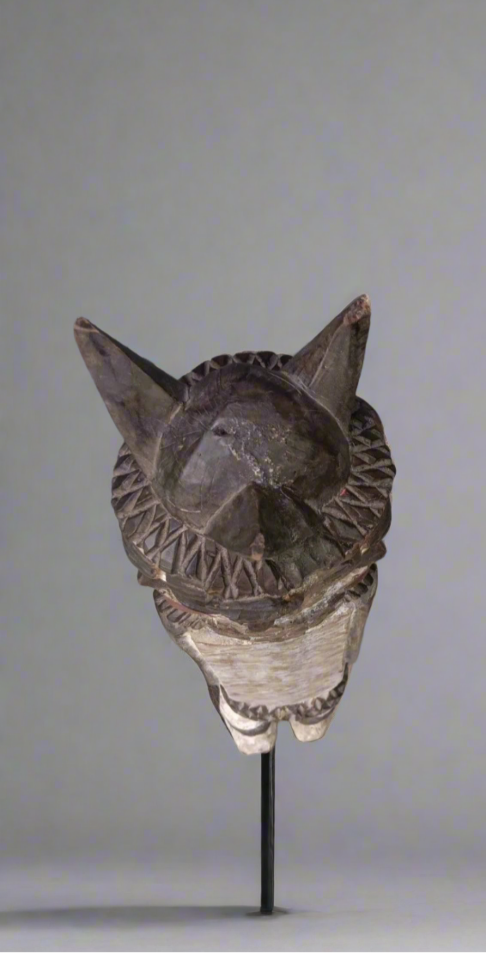 Decorative mask on a stand against a plain background